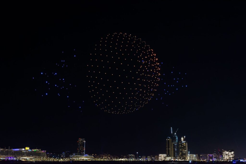 Illuminated blue drones glowing in the black night sky and forming circles